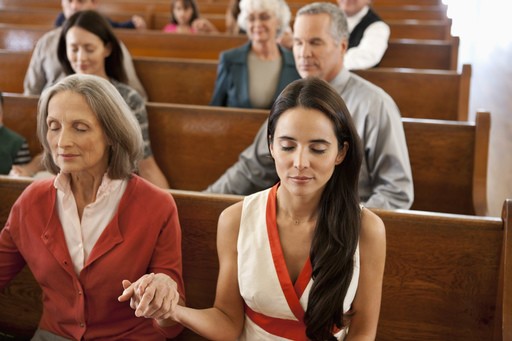 a25 Two women holding hands in church pews